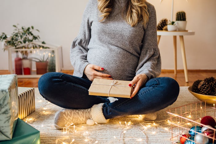 Pregnant woman sitting on floor wrapping Christmas presents