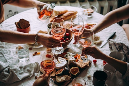 A group of friends toast glasses of rosé during a couples' dinner party.