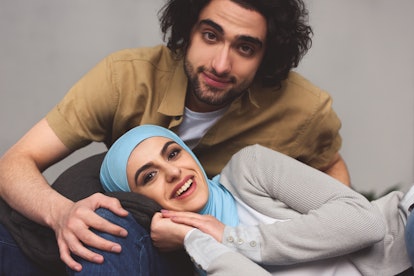 smiling muslim couple looking at camera at home