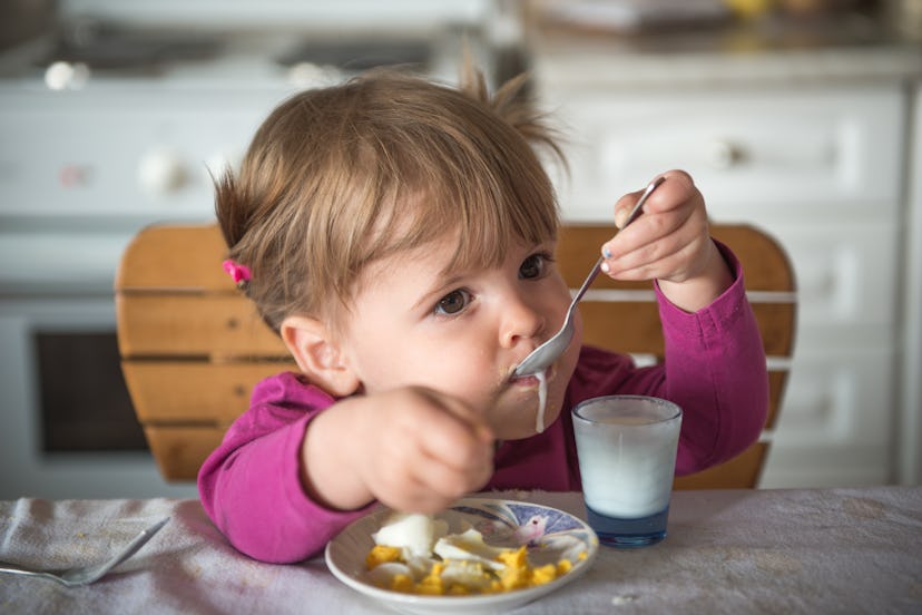 Cute girl eating beakfast and yogurt with spoon