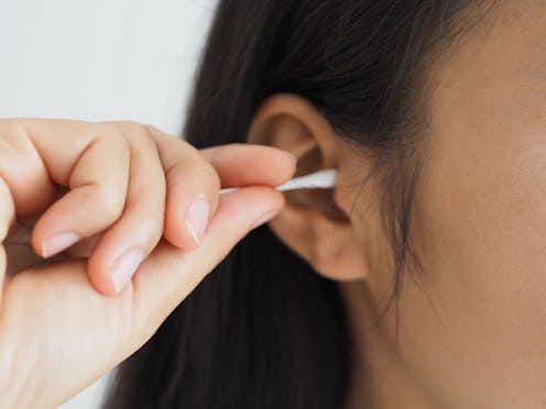 cerumen impaction or impacted earwax in asian woman. She use hand cleaning her ear with stick cotton...