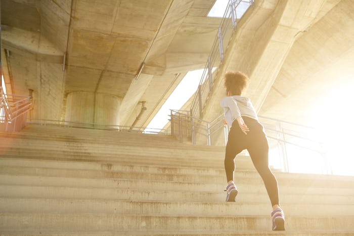 Young woman exercising, running alone up stairs