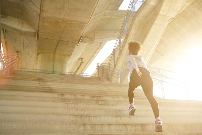 Young woman exercising, running alone up stairs 