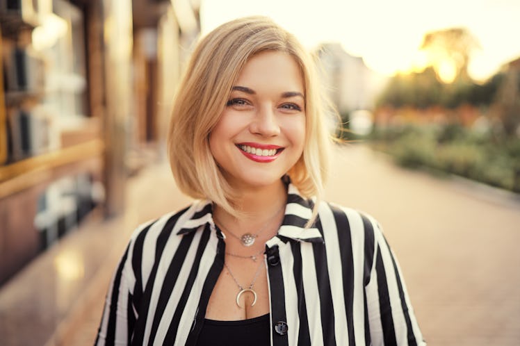 Outdoor portrait of happy young woman walking by city street.