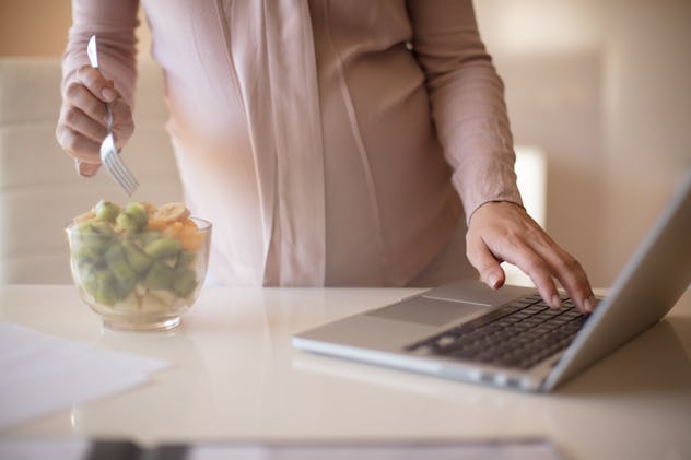 Take a break for a healthy snack. Pregnant woman eating fruit salad. Close up.