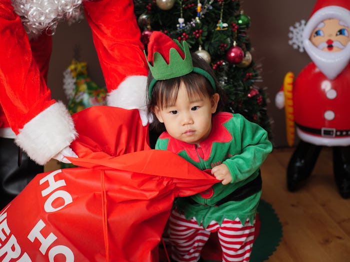 toddler pulling Christmas gift out of santa's bag