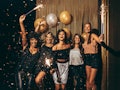 Shot best friends celebrating new year's eve holding sparklers in a party. Group of women having par...