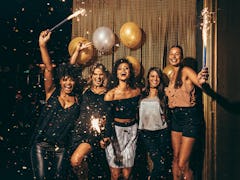 Shot best friends celebrating new year's eve holding sparklers in a party. Group of women having par...