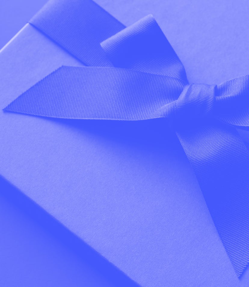 Black gift box on a dark contrasted background, decorated with a textured bow and feathers, creating...