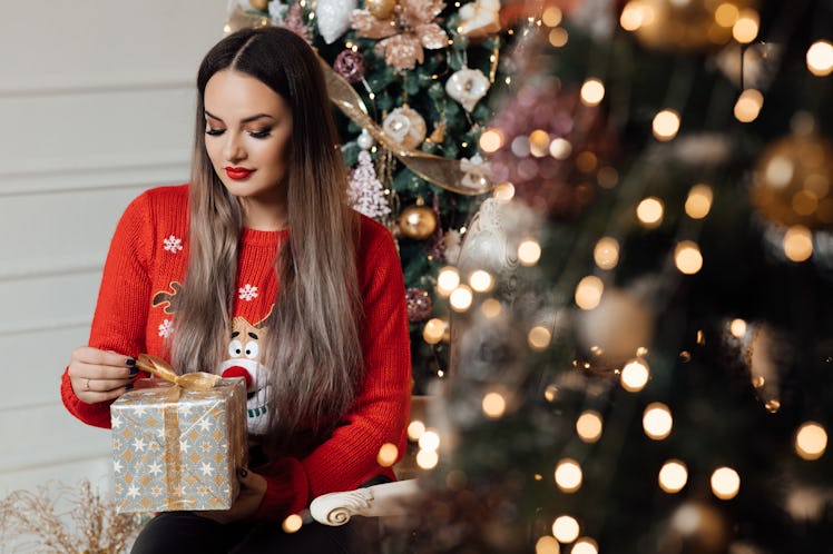 The girl holds gift box in her hands. Happy new year. Christmas. Beautiful smiling woman. Makeup. El...