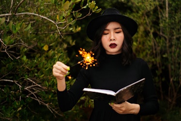 Black witch try to make a spell with her wand and magic book.