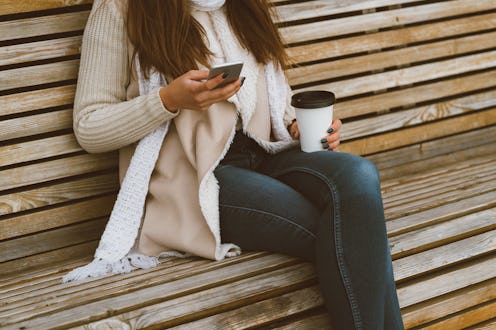 Unrecognizable beautiful young girl drinking coffee, tea from a plastic mug in autumn, winter and ta...