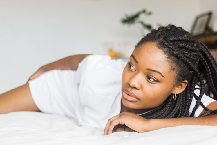 Sexy, Young African Female Model In An Oversized White T-Shirt Lying Down On A White Bed Looking Awa...