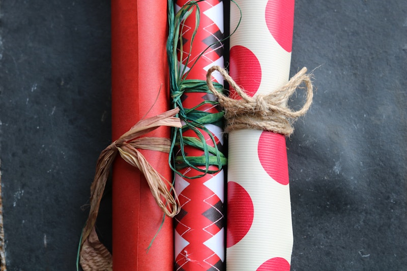 Three rolls of recycled wrapping paper on a piece of stone slate, in three different patterns; polka...