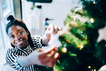 Young woman decorating her Christmas tree before posting Christmas tree captions on Instagram.