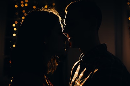silhouette of a man and a woman on a background of lights in the dark, contour of the face, a kissin...