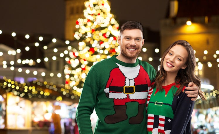 winter holidays, celebration and people concept - portrait of happy couple in ugly sweaters hugging ...