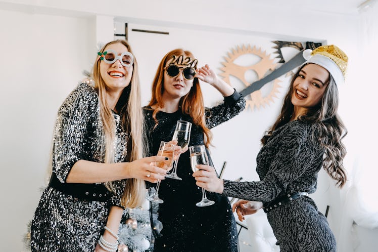 Cheers! New Year Eve, Christmas Celebration. Three partying girls clinking flutes with champagne. Yo...