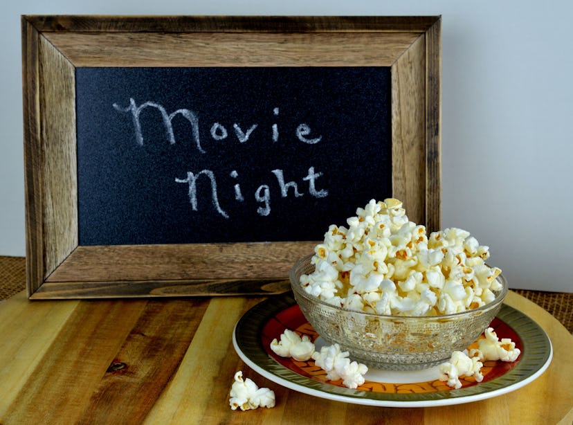 Freshly popped hot buttered homemade popcorn served in a bowl.  A sign suggesting movie night in the...