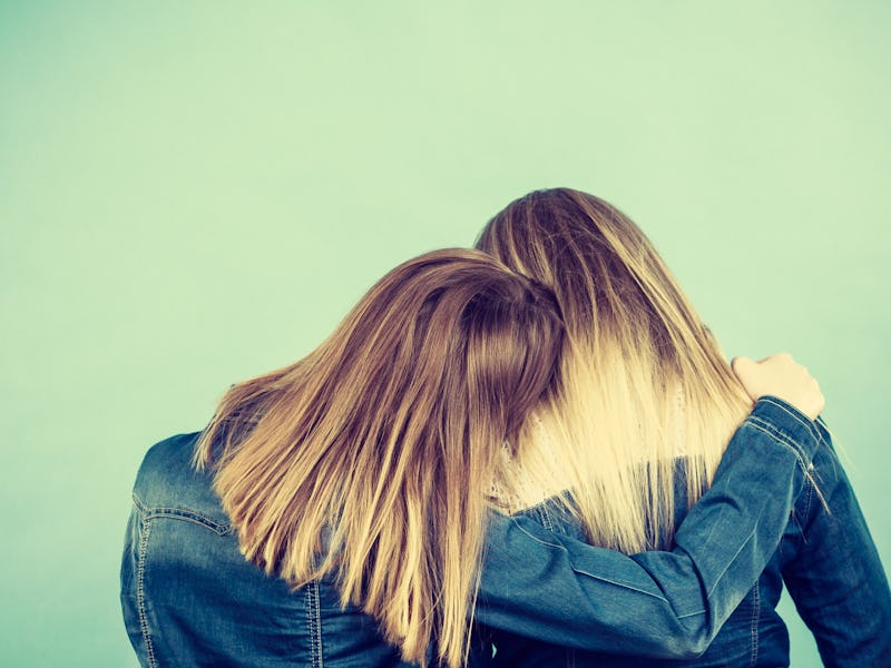 Back view of two unrecognizable blonde women hugging each other. Friendship, family love concept.