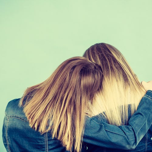 Back view of two unrecognizable blonde women hugging each other. Friendship, family love concept.