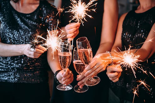 Friends celebrating Christmas or New Year eve party with Bengal lights and rose champagne.