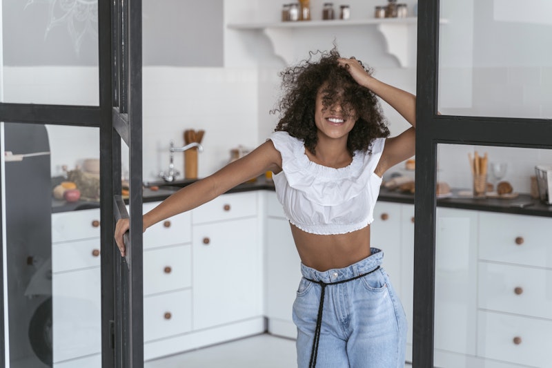 Young female smiling leaning on the door of her kitchen