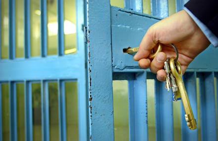 Police officers locks the door in prison corridor.