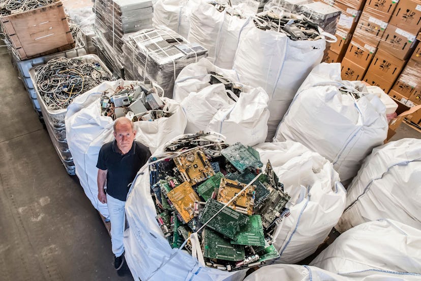 On, founder of the company, Out Of Use, Mark Adriaenssens, stands among bags of electronic parts and...