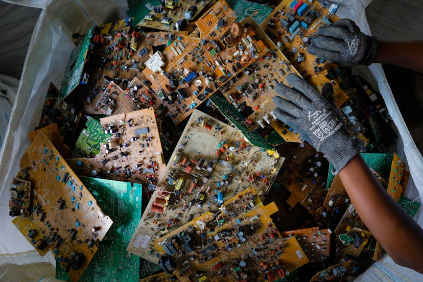 A worker picks up a motherboard seen in a basket before being shipped to Europe for safe processing ...
