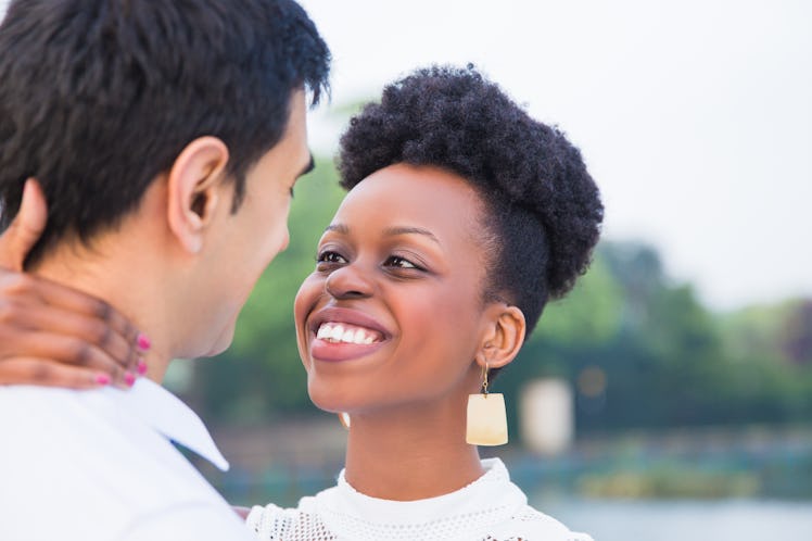 Close-up the young romantic smiling couple standing in embrace face to face in the park