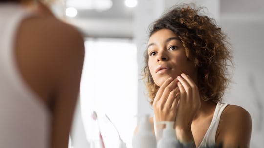 young woman looking at her face in the mirror