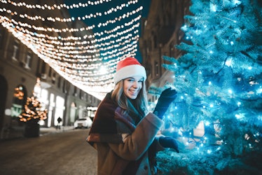 A happy woman shares her Christmas tree on Insta with Christmas tree puns for Instagram as her capti...