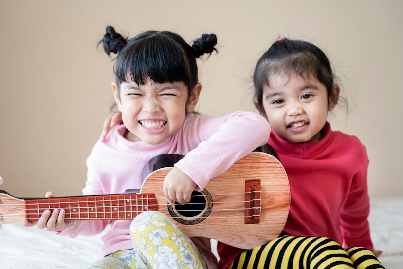 Kids playing guitar and singing the song of music together at home.