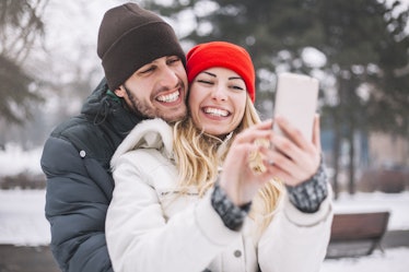 Happy couple taking selfie by smart phone in winter