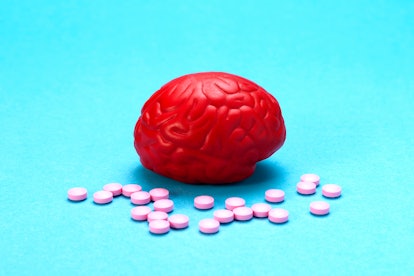 Red brain on a blue background with pink pills. Some pills for the brain. It is symbolic for drugs, ...