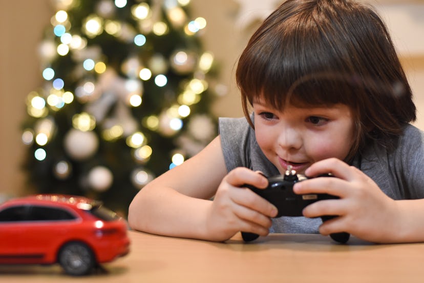 Happy boy play with car toys for Christmas. Smiling child having fun and playing with cars. Colorful...