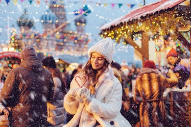 Girl walking in Christmas market decorated with holiday lights in the evening. Feeling happy in big ...