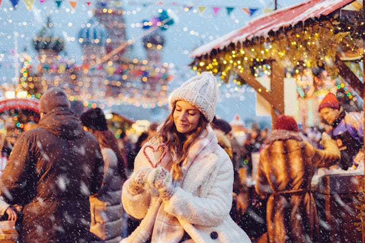 Girl walking in Christmas market decorated with holiday lights in the evening. Feeling happy in big ...