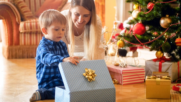 Toddler boy looking inside of CHristmas gift box with young mother