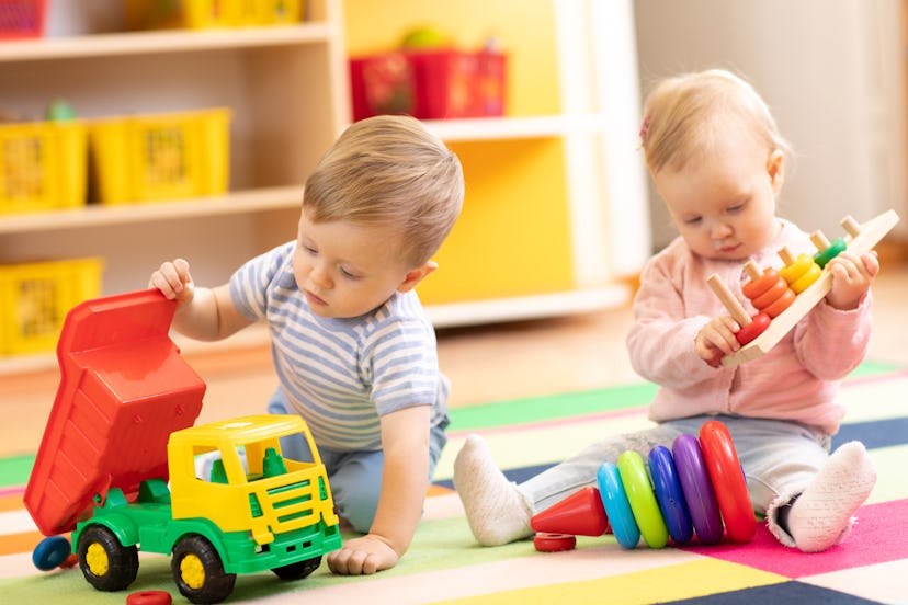 Kids playing with educational toys. Children sit on a rug in a play room at home or kindergarten. To...