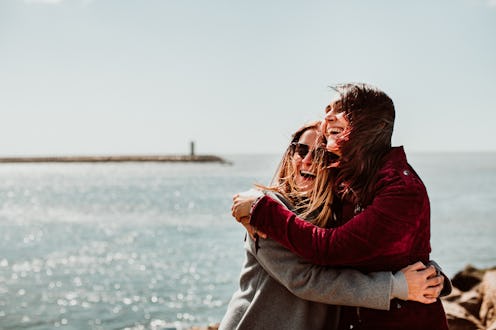 Lesbian couple laughing together on their trip to Porto in Portugal. Walking along the coast on a w...