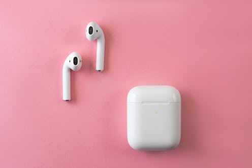 Air Pods. with Wireless Charging Case. New Airpods 2019 on pink background. Airpods. female headphon...