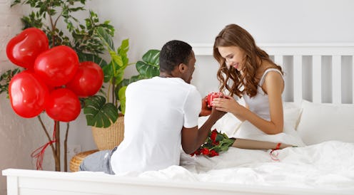 Valentine's Day. happy couple in love with red hert and flowers in bed