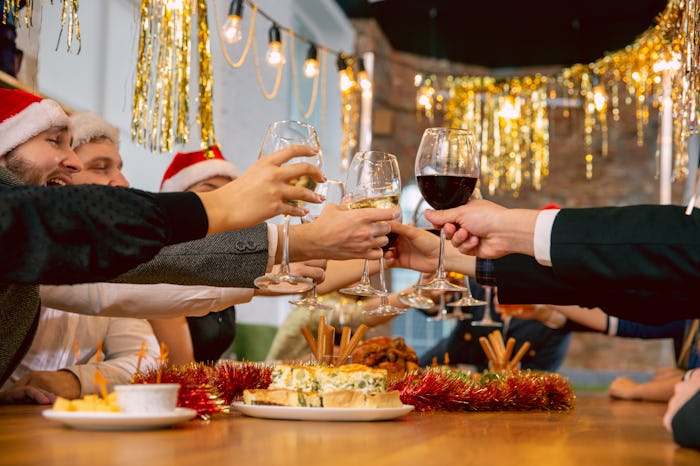 people toasting each other at a Christmas party over a table of food