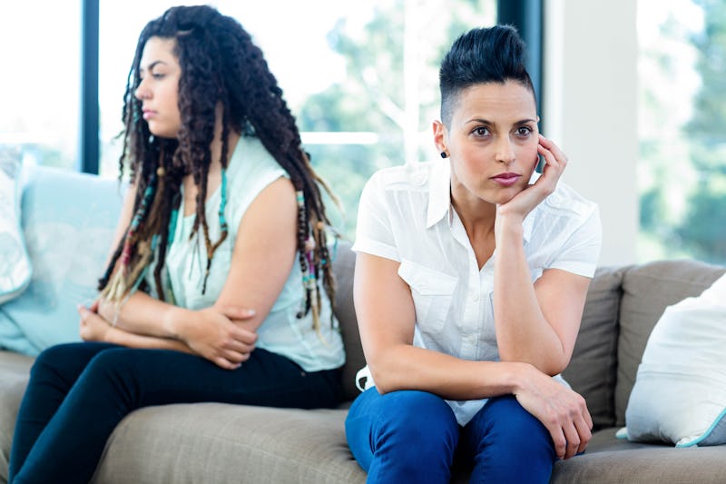 Unhappy lesbian couple sitting on sofa in living room