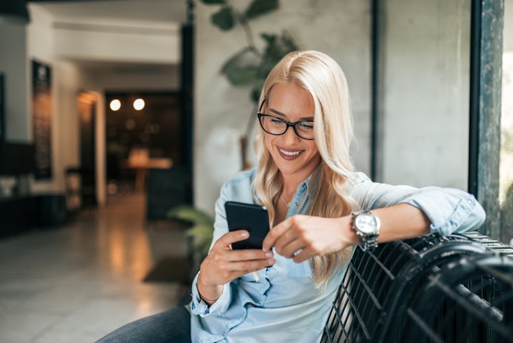 Close-up image of gorgeous blonde woman texting indoors.