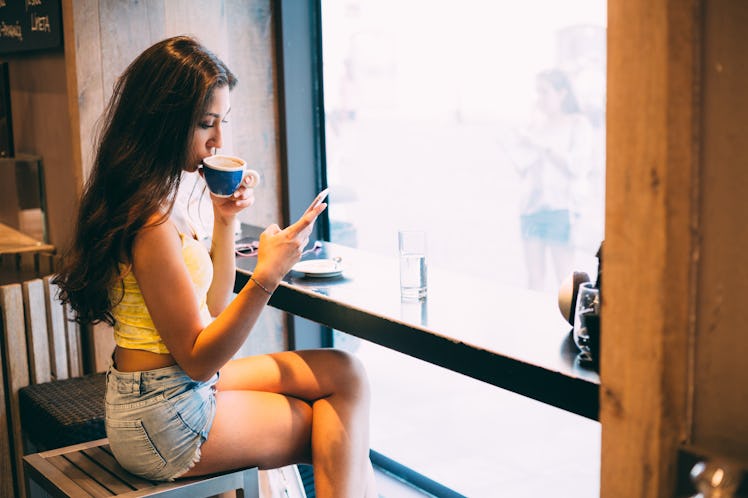 Young millennial woman texting in coffee shop