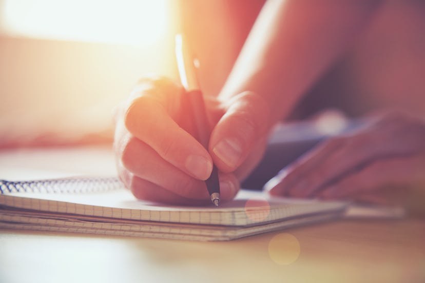 female hands with pen writing on notebook