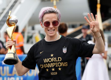 Megan Rapinoe holds the Women's World Cup trophy mafter she and other embers of the U.S. soccer team...